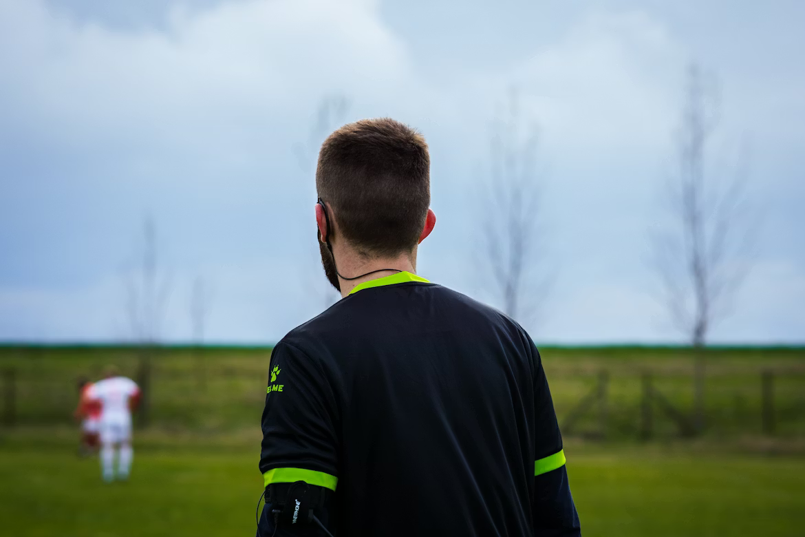 Sports referee wearing HYPƐAR custom in-ear monitors for hearing protection during games - Swedish-made 3D-printed custom-fit hearing protection protecting from crowd noise and game sounds while maintaining ability to hear important audio cues and communication